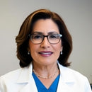 Dentist wearing glasses and lab coat smiling.