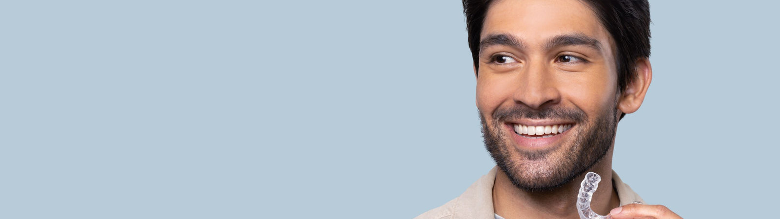 Man smiling while holding a Chomper Labs night guard.
