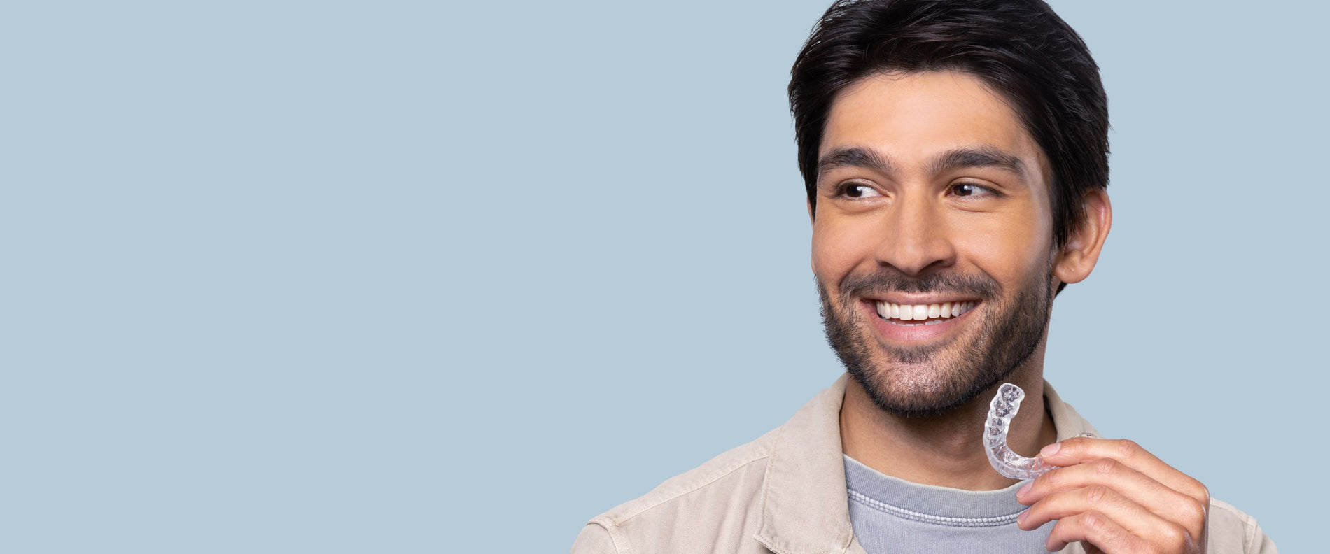 Man smiling while holding a Chomper Labs night guard.
