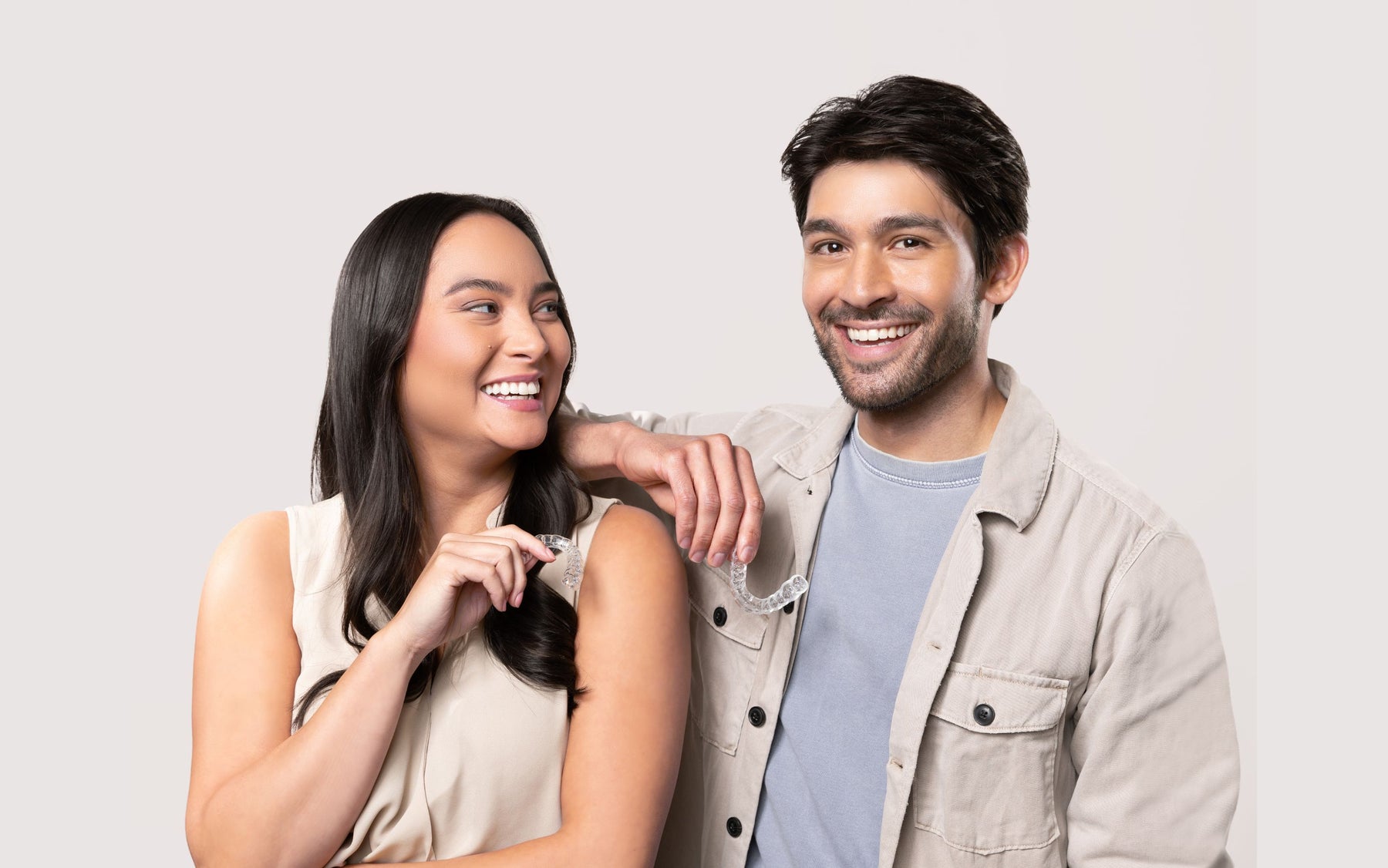 Two people smiling and holding Chomper Labs night guards.
