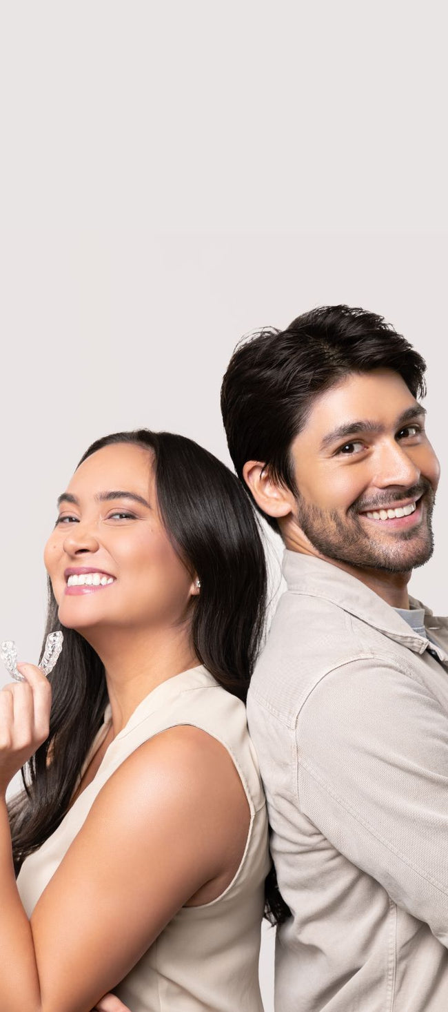 Two people smiling and holding Chomper Labs night guards.