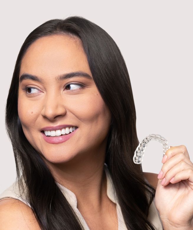 Woman smiling while holding a Chomper Labs night mouth guard.