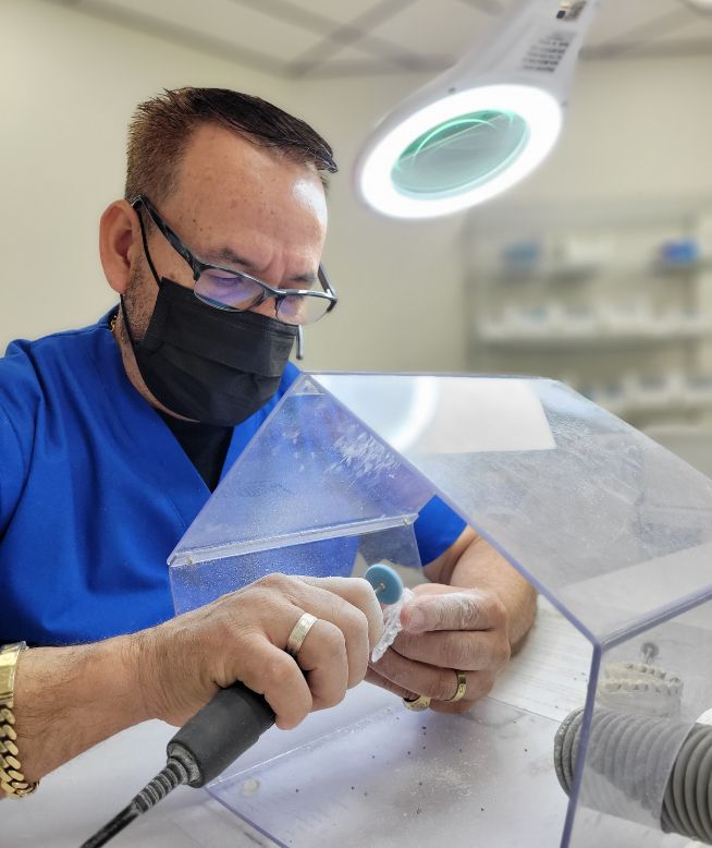 Dental lab technician carefully cutting a night guard.