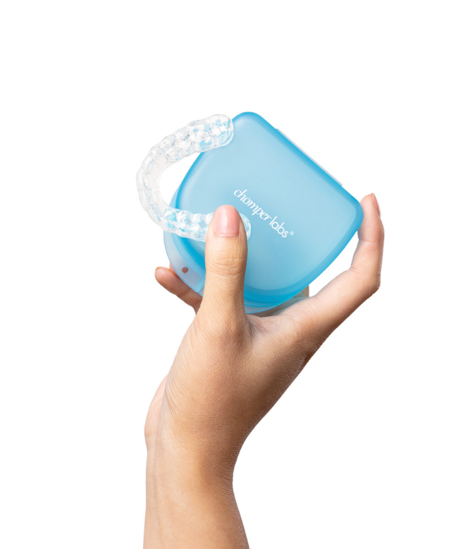 Hand holding a Chomper Labs night guard and blue container case.