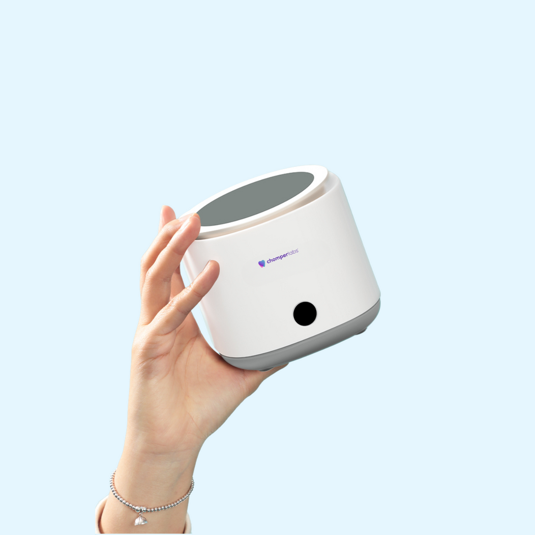 Hand holding Chomper Labs ultrasonic cleaner for night guards.